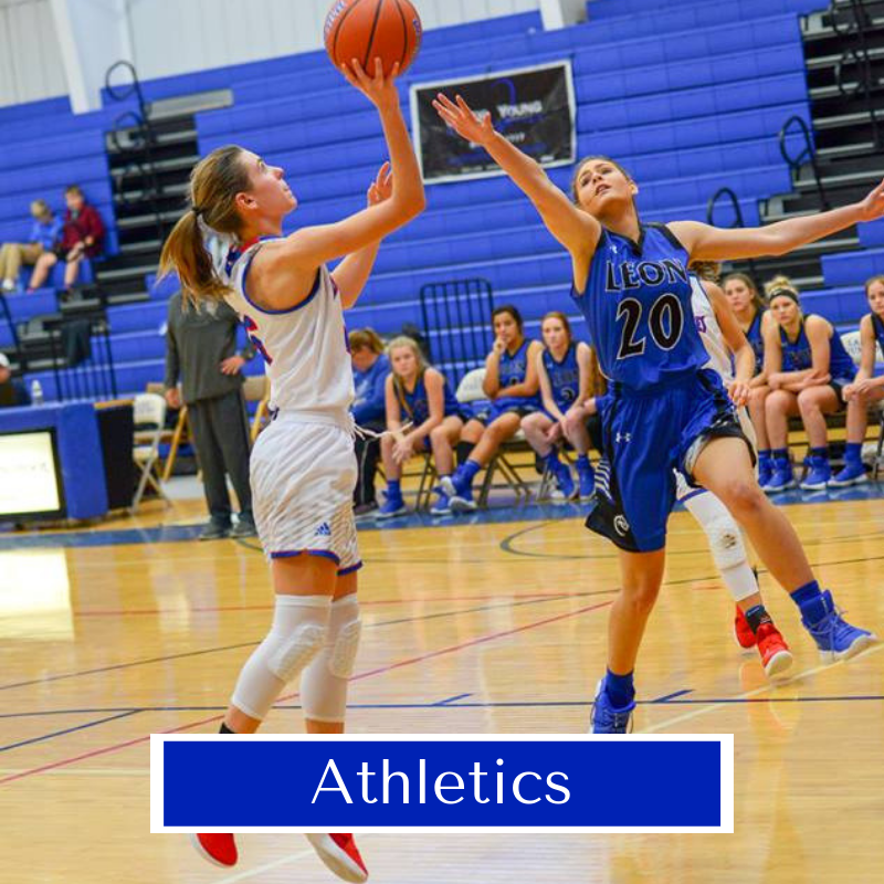 Photo of two basketball players as one shoots a baskets.