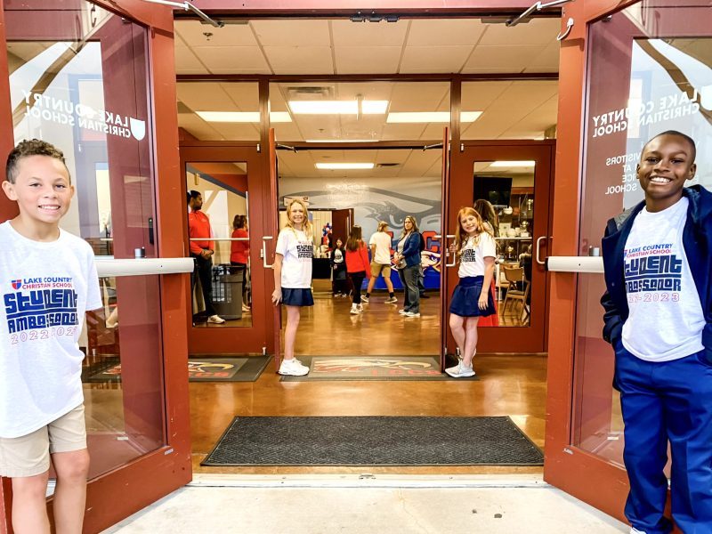 students holding the doors open for guests