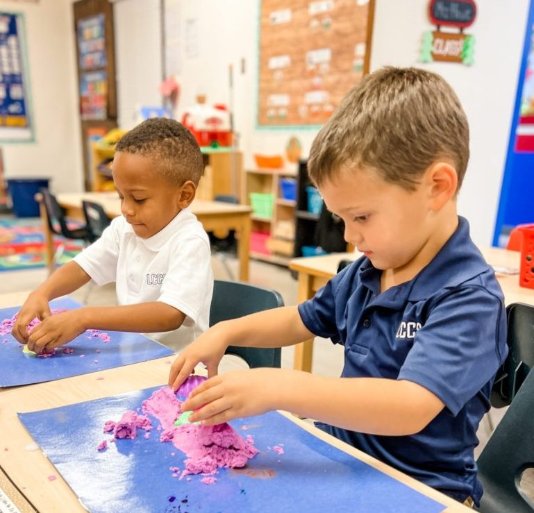 two children at a table playing with play doh